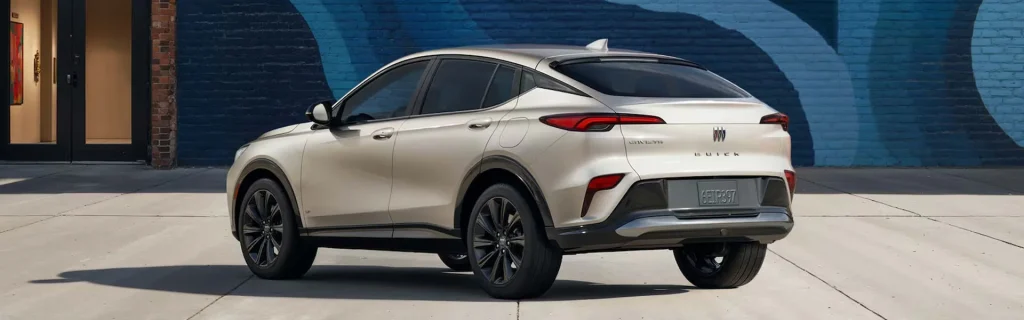 This image shows a rear view of a 2026 Buick Envista SUV parked in front of a colorful mural, featuring sleek, modern design elements and dark rims.